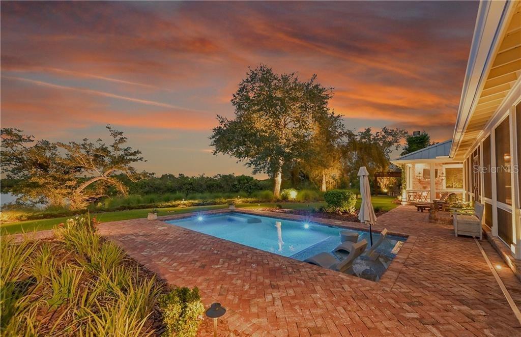 A backyard swimming pool with a brick patio at sunset near a house — 27300 EGRET PLACE, PUNTA GORDA, FL