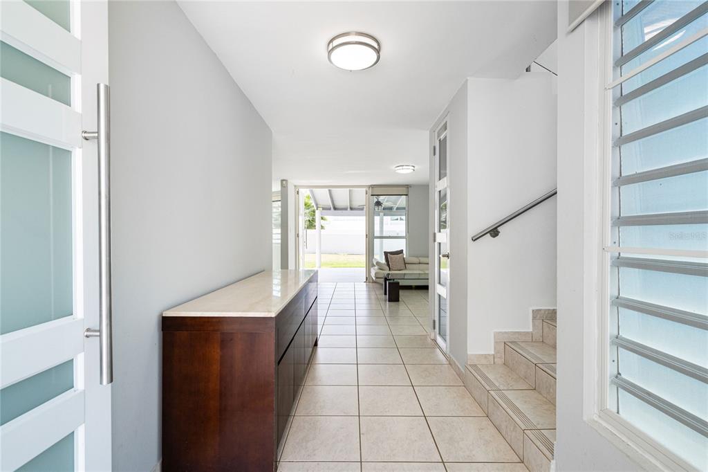 A tiled entryway features a wooden console table, a staircase, and a view of the patio — 357 SABALO STREET, DORADO, PR