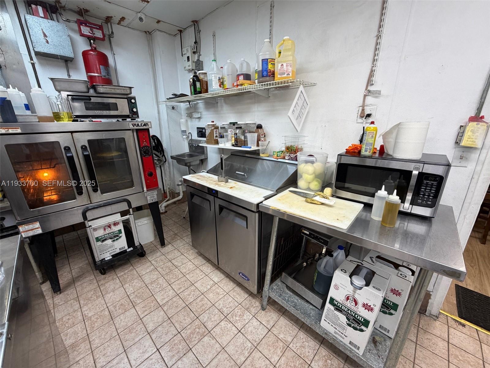 A commercial kitchen features stainless steel appliances, a prep station, and tiled flooring — 7500 NW 25th St, Miami FL 33122, MIAMI, FL