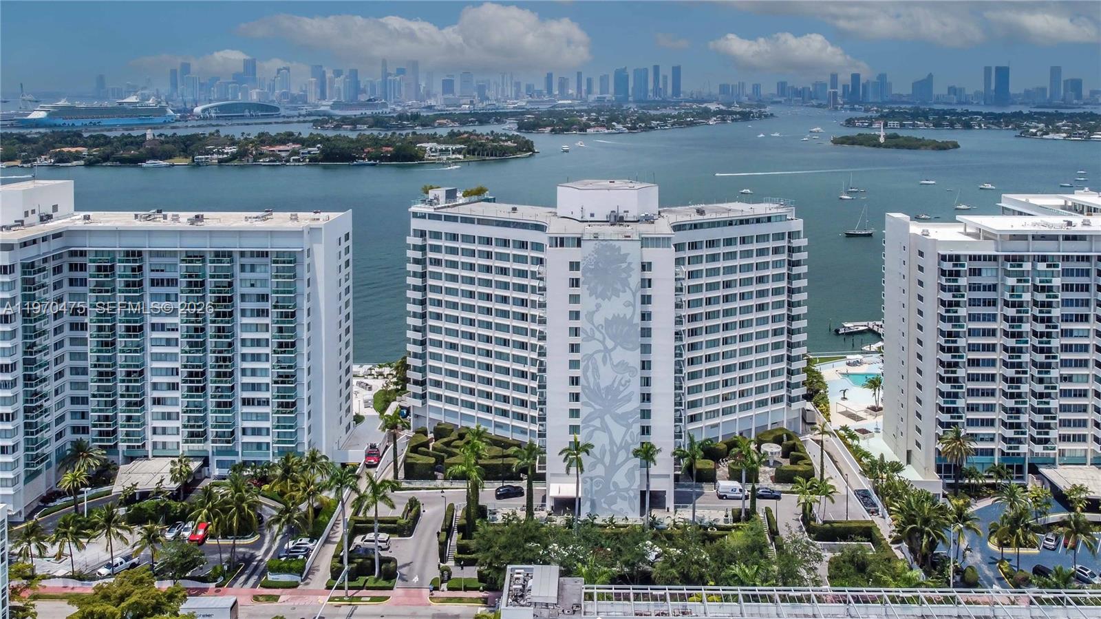 An aerial view shows three white high-rise residential buildings situated along a waterfront in Miami — 1100 West Ave # 322, Miami Beach FL 33139, MIAMI BEACH, FL