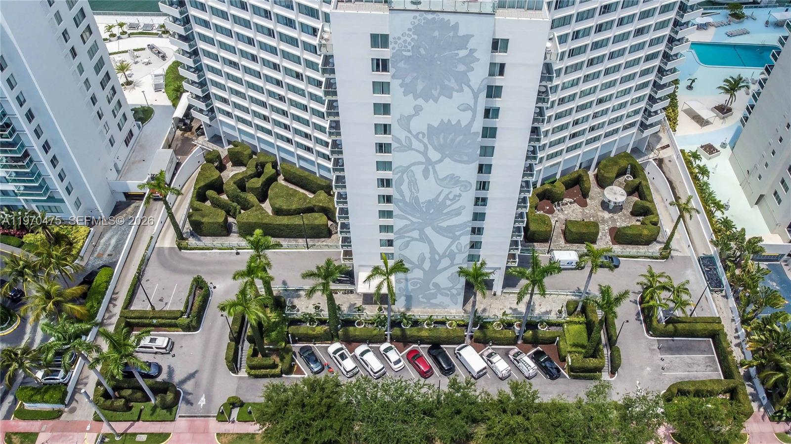 An aerial view shows a tall residential building with a floral mural and landscaped grounds — 1100 West Ave # 322, Miami Beach FL 33139, MIAMI BEACH, FL