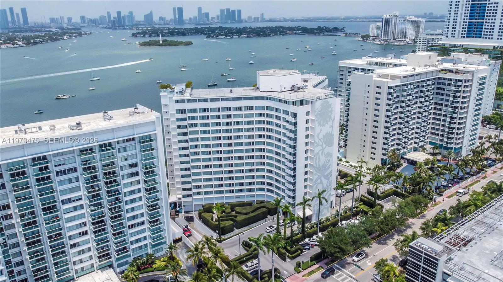 An aerial view shows a white high-rise building surrounded by palm trees and water — 1100 West Ave # 322, Miami Beach FL 33139, MIAMI BEACH, FL