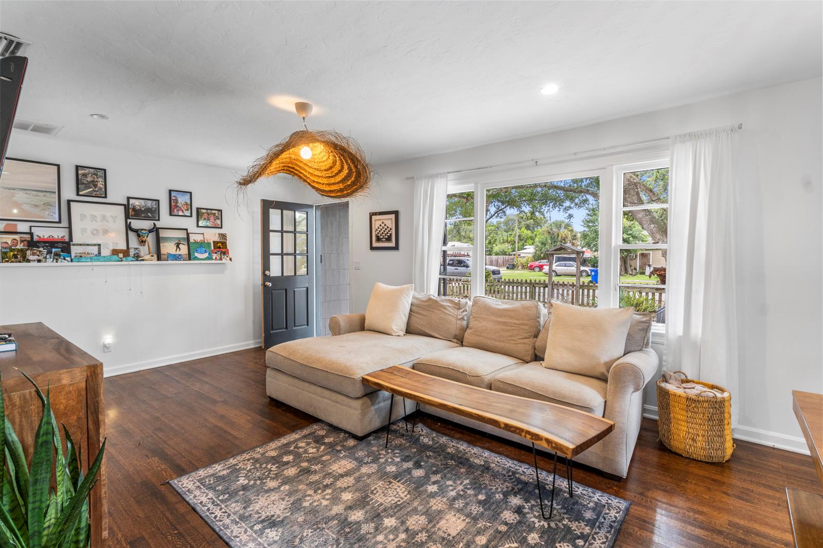 A living room features a sectional sofa, a live-edge coffee table, and a woven pendant light — VERO BEACH, FL