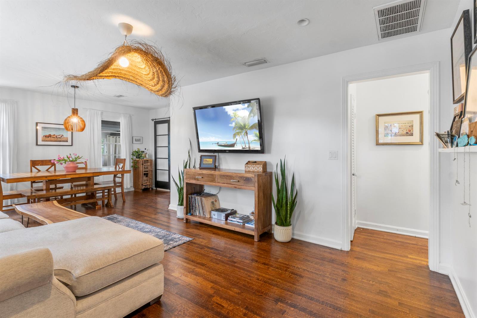 A living room features hardwood floors, a mounted television, a wooden console, and dining area — VERO BEACH, FL