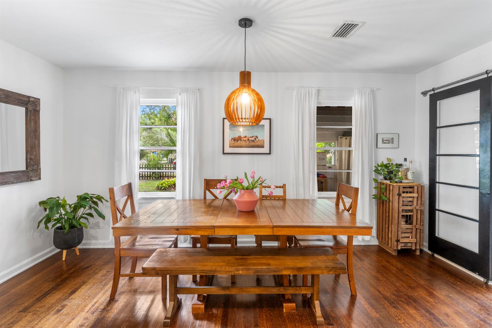 A dining room features a wooden table, bench, chairs, pendant light, and hardwood floors — VERO BEACH, FL