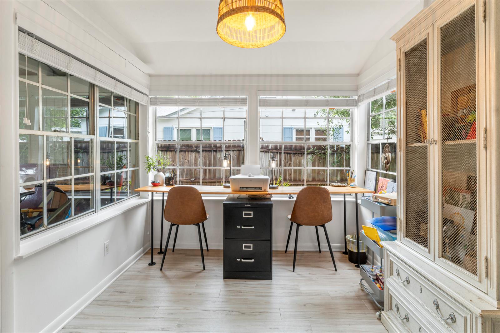 A sunroom features a long wooden desk with two chairs, a printer, and light flooring — VERO BEACH, FL