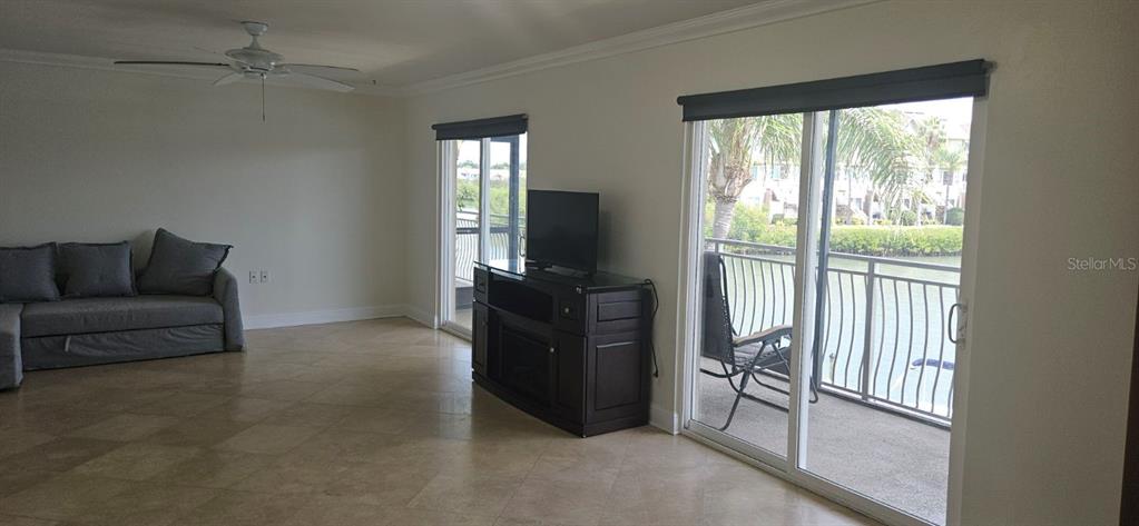 A living room features tile floors, a gray sofa, a television console, and sliding glass doors — 8822 BAY POINTE DRIVE UNIT 203, TAMPA, FL