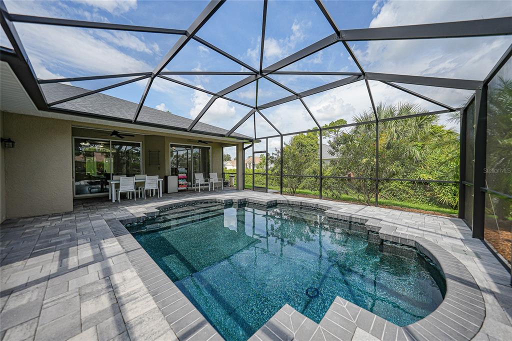 A screened-in patio features a swimming pool with stone pavers and outdoor dining furniture — 2880 VOGLER LANE, NORTH PORT, FL