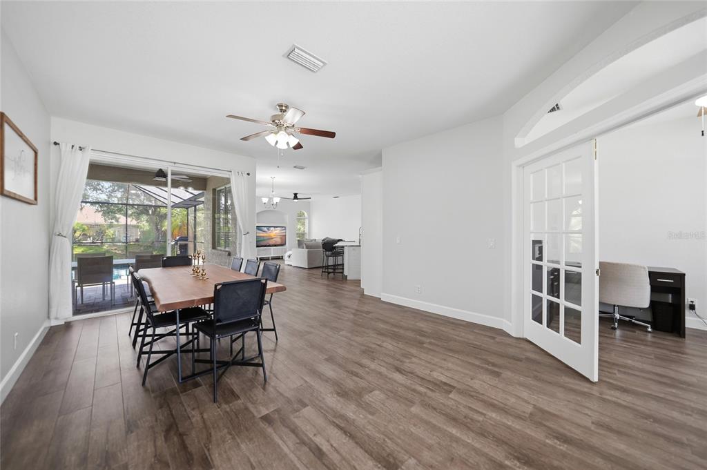 A dining area with a wood table and chairs opens to a patio and office — 2880 VOGLER LANE, NORTH PORT, FL