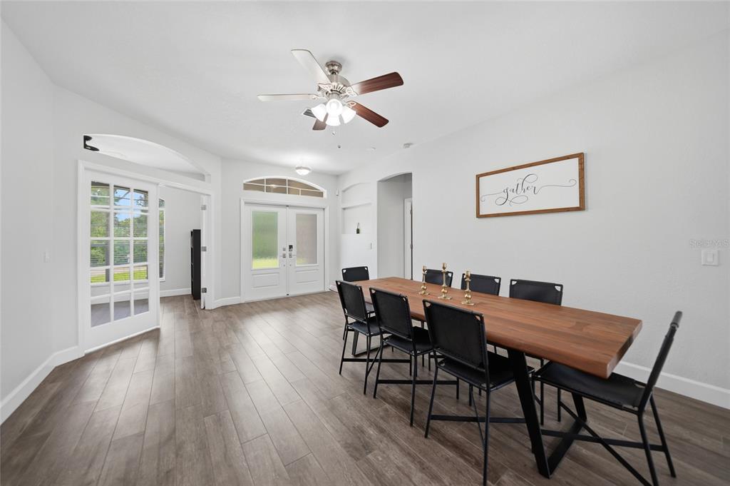 A dining room features a long wooden table, black chairs, and light wood flooring — 2880 VOGLER LANE, NORTH PORT, FL