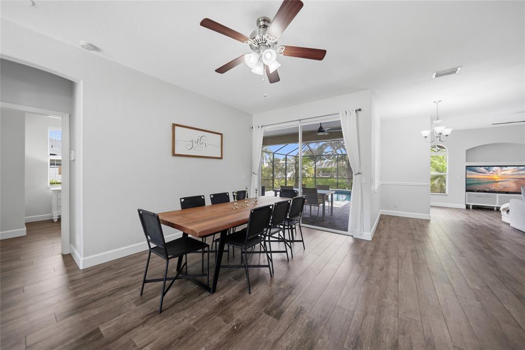 A dining room with a wooden table, black chairs, and sliding glass doors to a pool — 2880 VOGLER LANE, NORTH PORT, FL