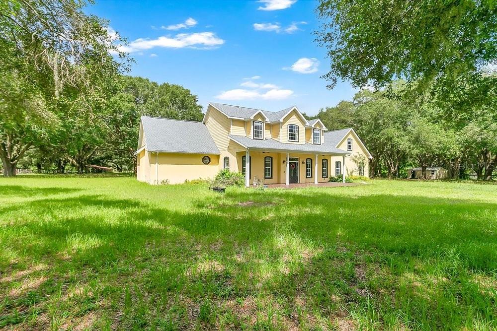 A yellow two-story house with a covered porch sits on a large, grassy lot — 3700 SE 183RD AVENUE ROAD, OCKLAWAHA, FL