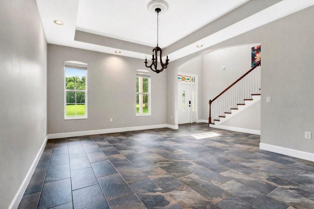 A dining room with gray walls, tile flooring, a tray ceiling, and a wooden chandelier — 3700 SE 183RD AVENUE ROAD, OCKLAWAHA, FL