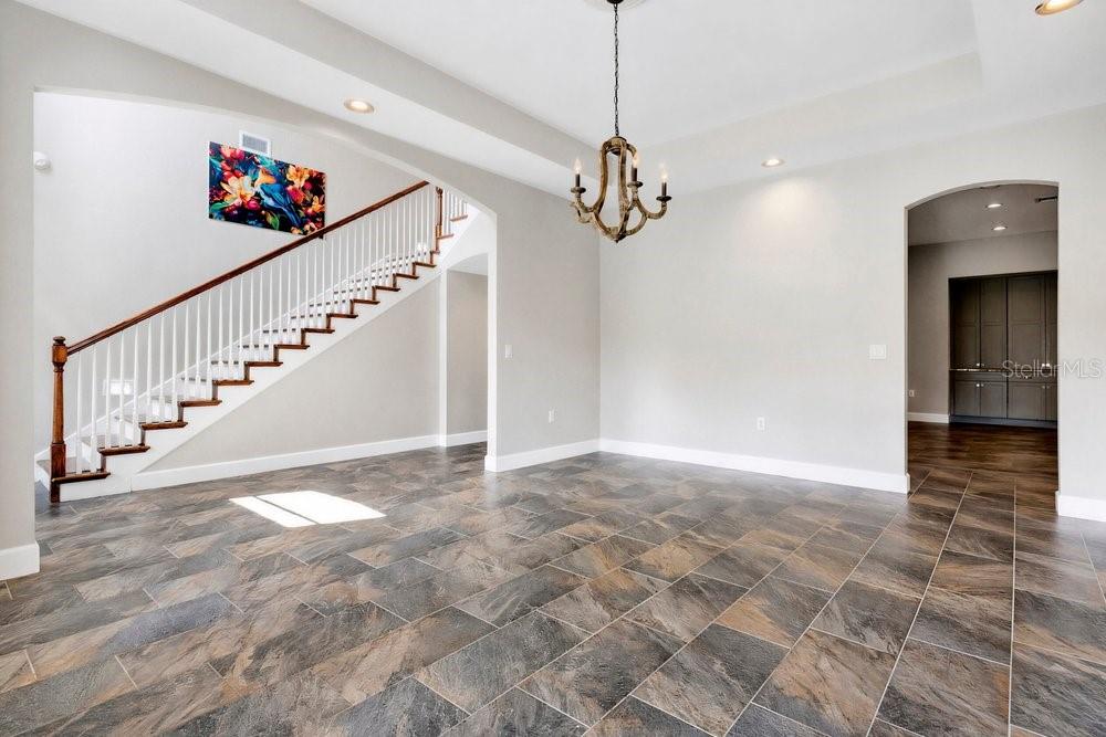 A dining room with tile flooring, a wooden chandelier, and a staircase with white railings — 3700 SE 183RD AVENUE ROAD, OCKLAWAHA, FL
