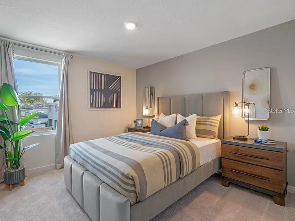 A bedroom features a gray upholstered bed, a wooden nightstand, and a large window — 117 MYRTLE STREET, LONGWOOD, FL
