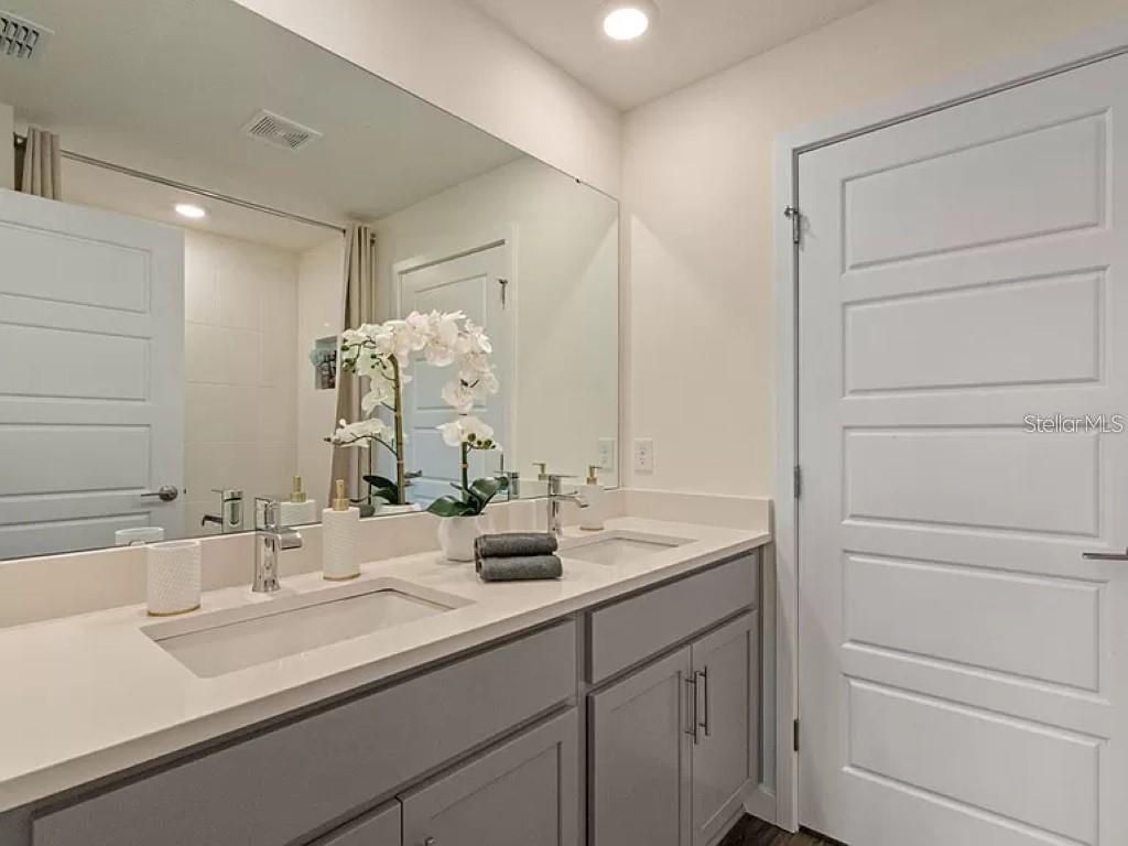 A bathroom features a double vanity with gray cabinets, white countertops, and a large mirror — 117 MYRTLE STREET, LONGWOOD, FL