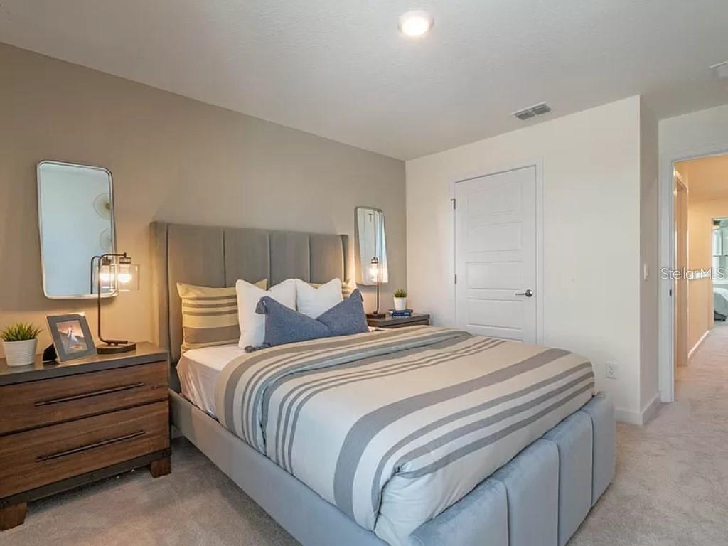 A bedroom features a gray upholstered bed, two nightstands with lamps, and wall-mounted mirrors — 117 MYRTLE STREET, LONGWOOD, FL