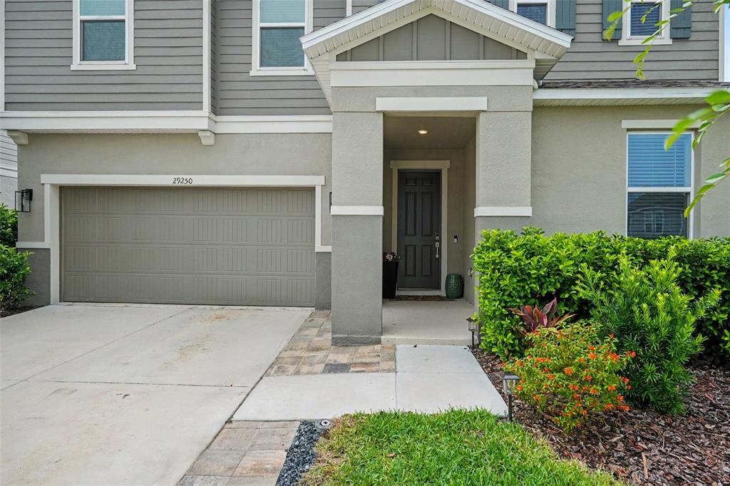 A two-story house features a gray garage, a covered entryway, and a landscaped front yard — 29250 KINSINGTON COURT, WESLEY CHAPEL, FL