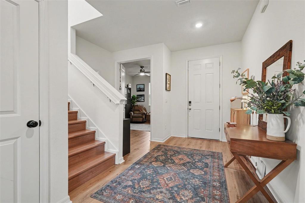An entryway features wood stairs, a patterned rug, a console table, and a white door — 29250 KINSINGTON COURT, WESLEY CHAPEL, FL
