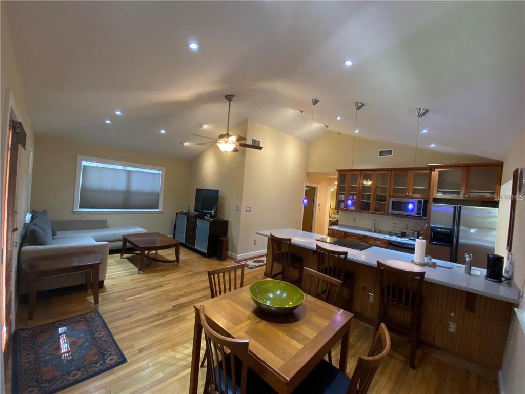 An open-concept living and dining area features hardwood floors, a kitchen island, and vaulted ceilings — 201 N GLENWOOD AVENUE, ORLANDO, FL