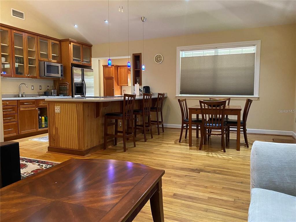 A kitchen with wood cabinets and an island opens to a dining area with hardwood floors — 201 N GLENWOOD AVENUE, ORLANDO, FL