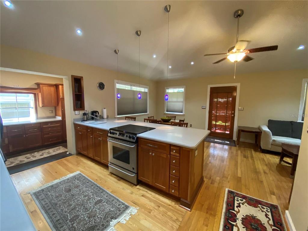 A kitchen with wood cabinets, a center island, and hardwood floors opens into a living area — 201 N GLENWOOD AVENUE, ORLANDO, FL