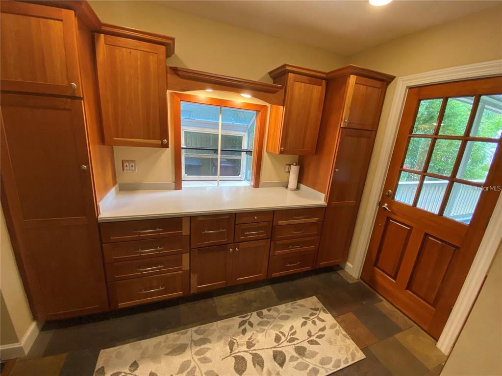 A kitchen features wood cabinets, white countertops, a window, and a glass-paneled door — 201 N GLENWOOD AVENUE, ORLANDO, FL