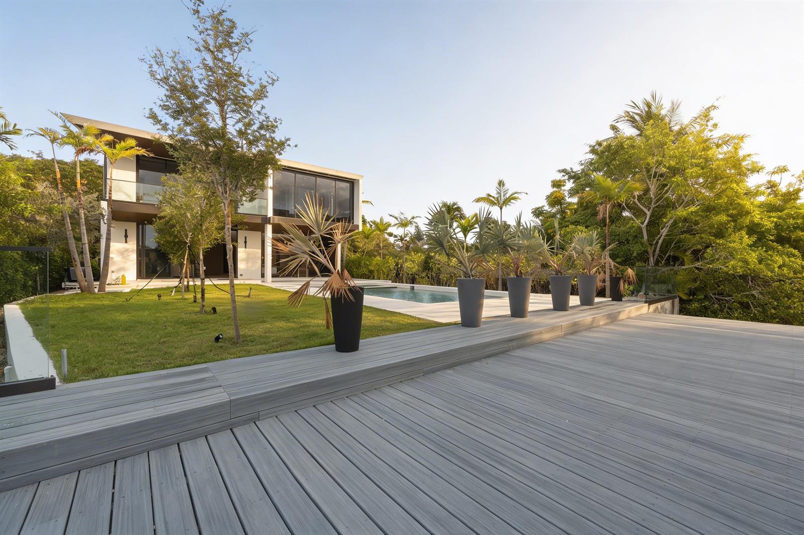 A modern house with a large wooden deck, swimming pool, and potted palm trees — 930 S Shore Drive, Miami Beach FL 33141, MIAMI BEACH, FL