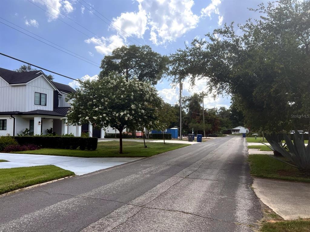 A paved street leads past a modern white house with a blooming tree in front — 2831 MULFORD AVENUE, WINTER PARK, FL