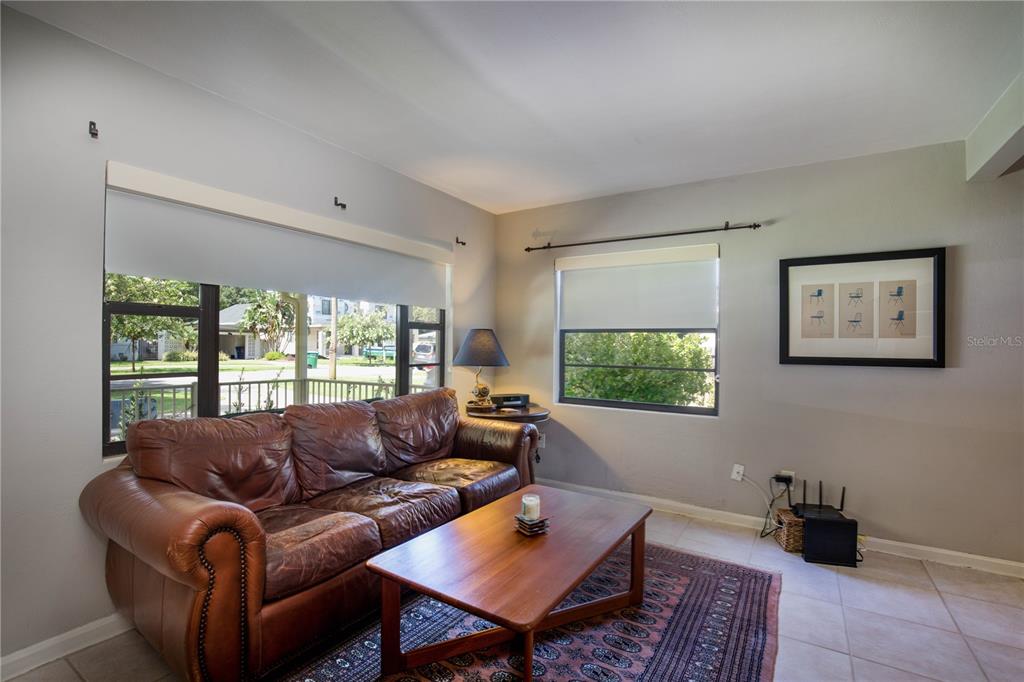 A living room features a brown leather sofa, a wooden coffee table, and tile flooring — 2831 MULFORD AVENUE, WINTER PARK, FL