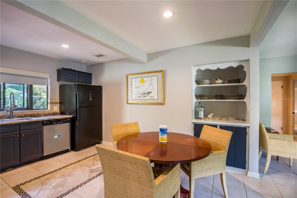 A kitchen with dark cabinets, a black refrigerator, a round dining table, and built-in shelving — 2831 MULFORD AVENUE, WINTER PARK, FL