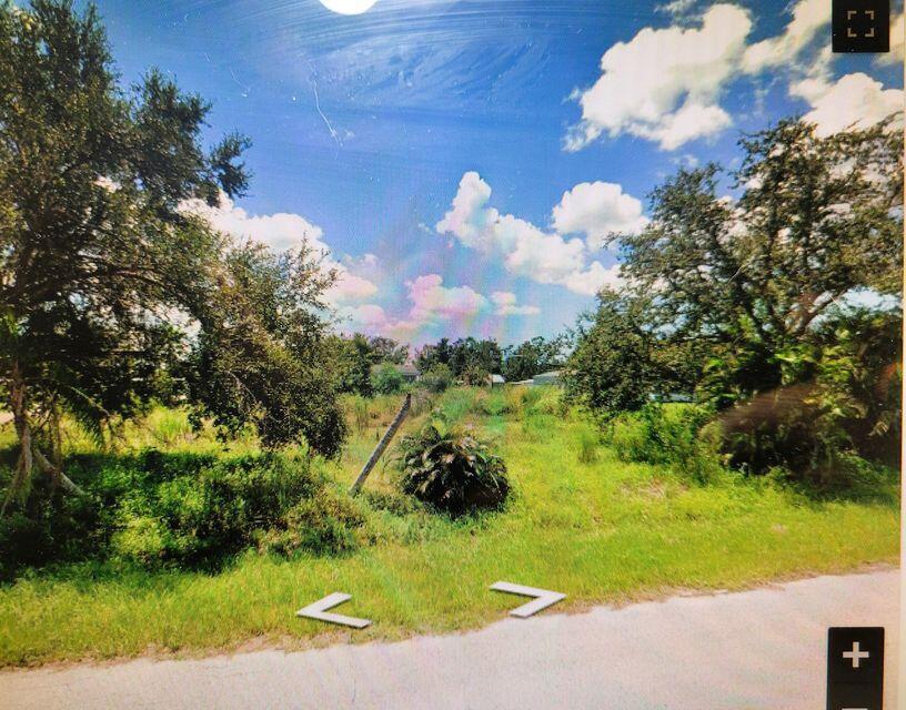 A vacant, grassy lot with mature trees under a blue sky with white clouds — 5385 Maze Drive, Punta Gorda FL 33982, PUNTA GORDA, FL