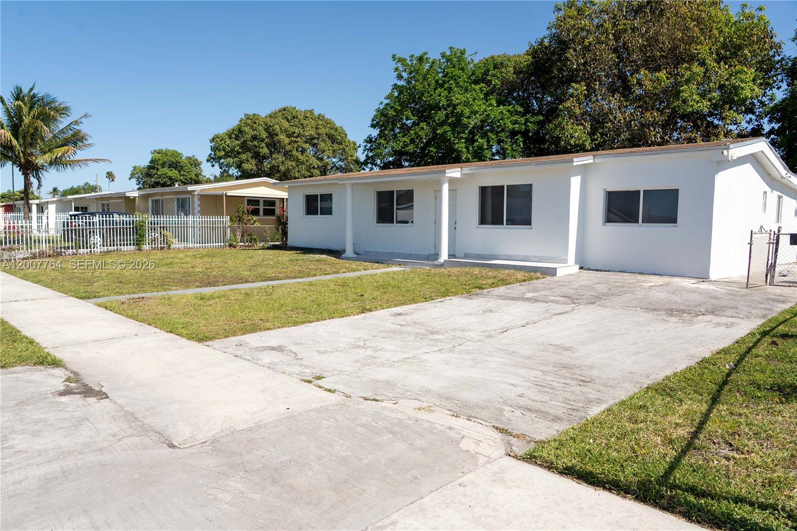 A white single-story house features a concrete driveway and a front lawn — 4000 NW 195th St, Miami Gardens FL 33055, MIAMI GARDENS, FL