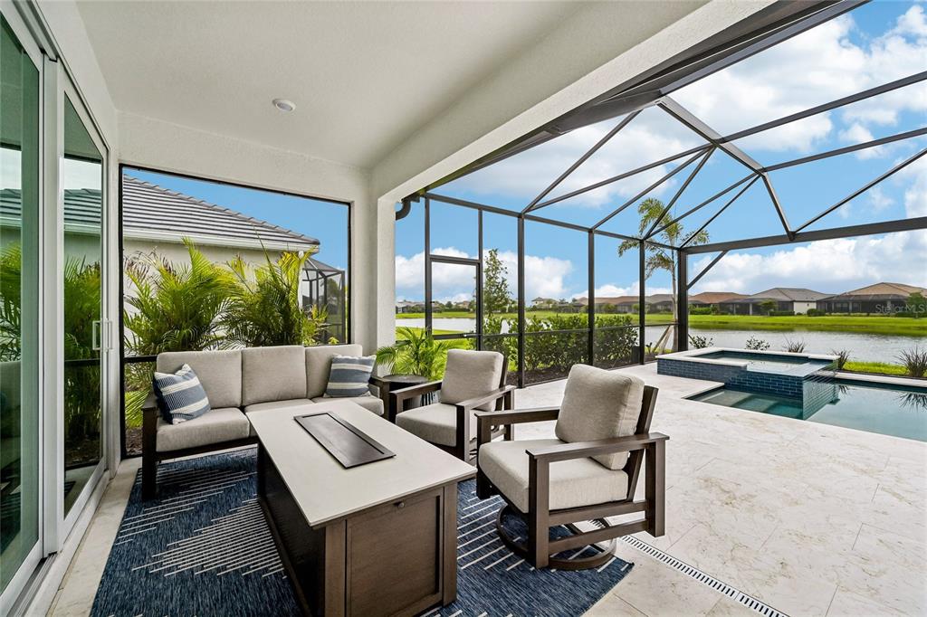 A covered patio features outdoor furniture, a fire pit table, and a pool with a spa — 3362 ALBA CIRCLE, BRADENTON, FL