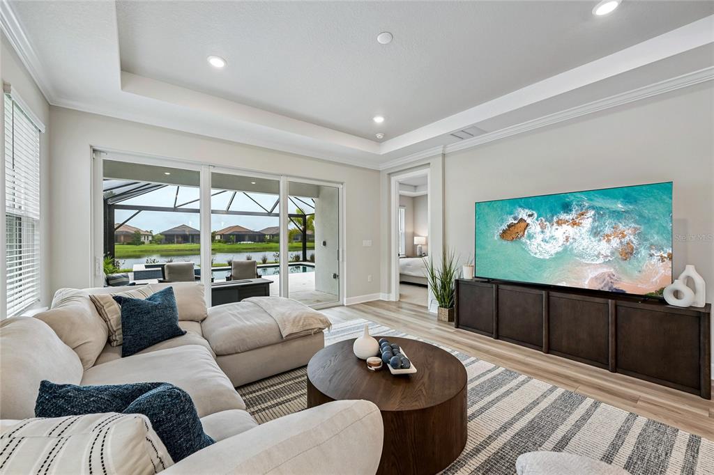 A living room features a sectional sofa, a large television, and sliding doors to a pool — 3362 ALBA CIRCLE, BRADENTON, FL
