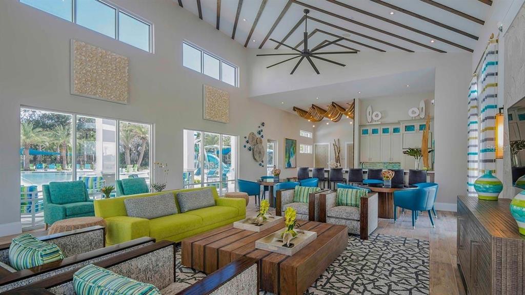A spacious, high-ceilinged lounge area features a lime green sofa, patterned armchairs, and a bar — 2374 RAMA DRIVE, KISSIMMEE, FL