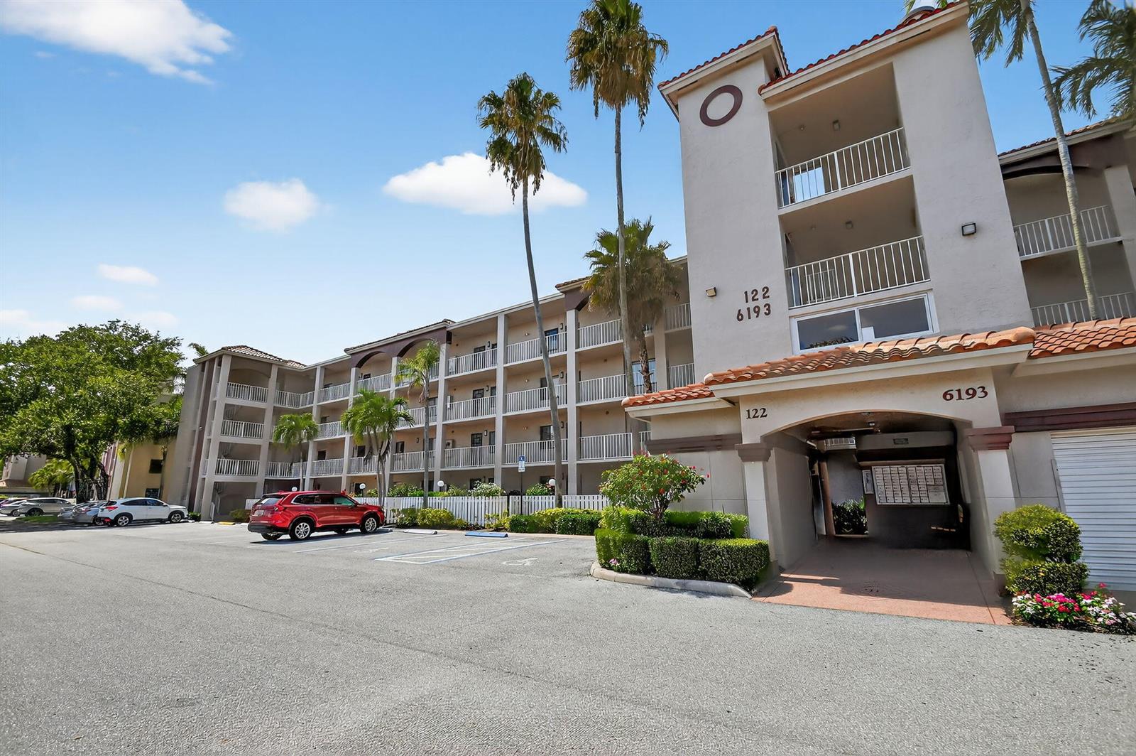 A multi-story apartment building with balconies, palm trees, and a parking lot in front — 6193 Pointe Regal Circle # 402, Delray Beach FL 33484, DELRAY BEACH, FL