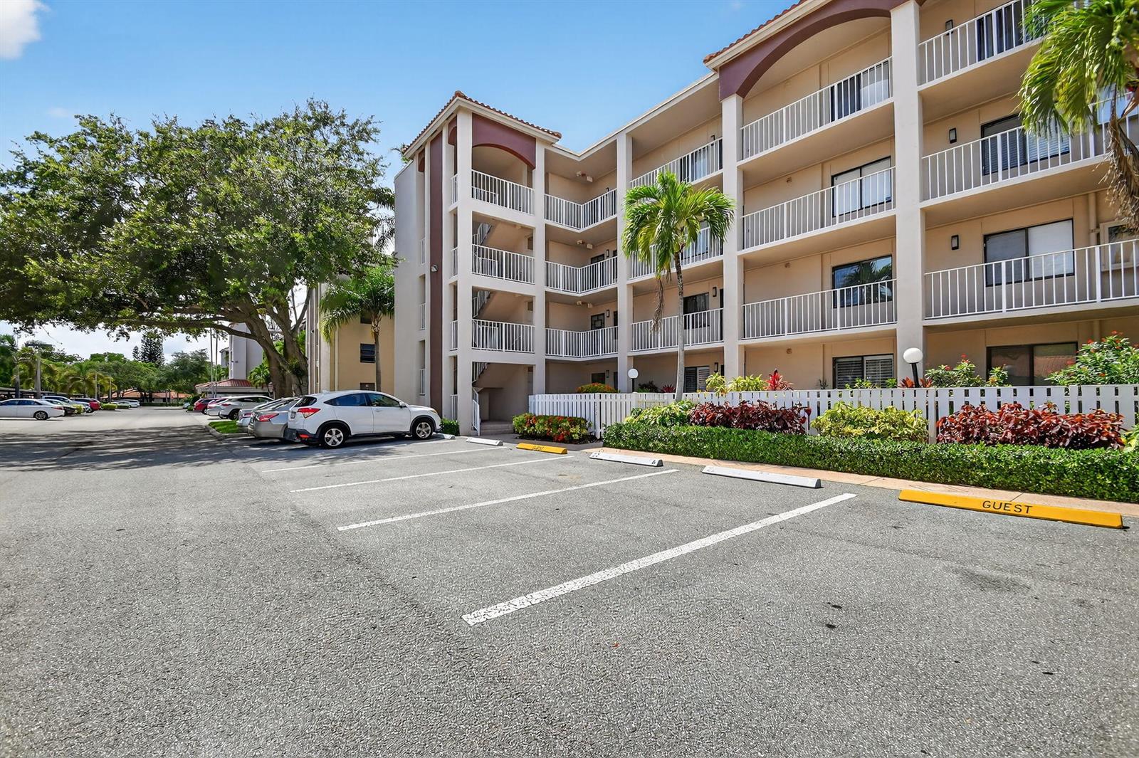 An exterior view of a multi-story apartment building with a parking lot in the foreground — 6193 Pointe Regal Circle # 402, Delray Beach FL 33484, DELRAY BEACH, FL