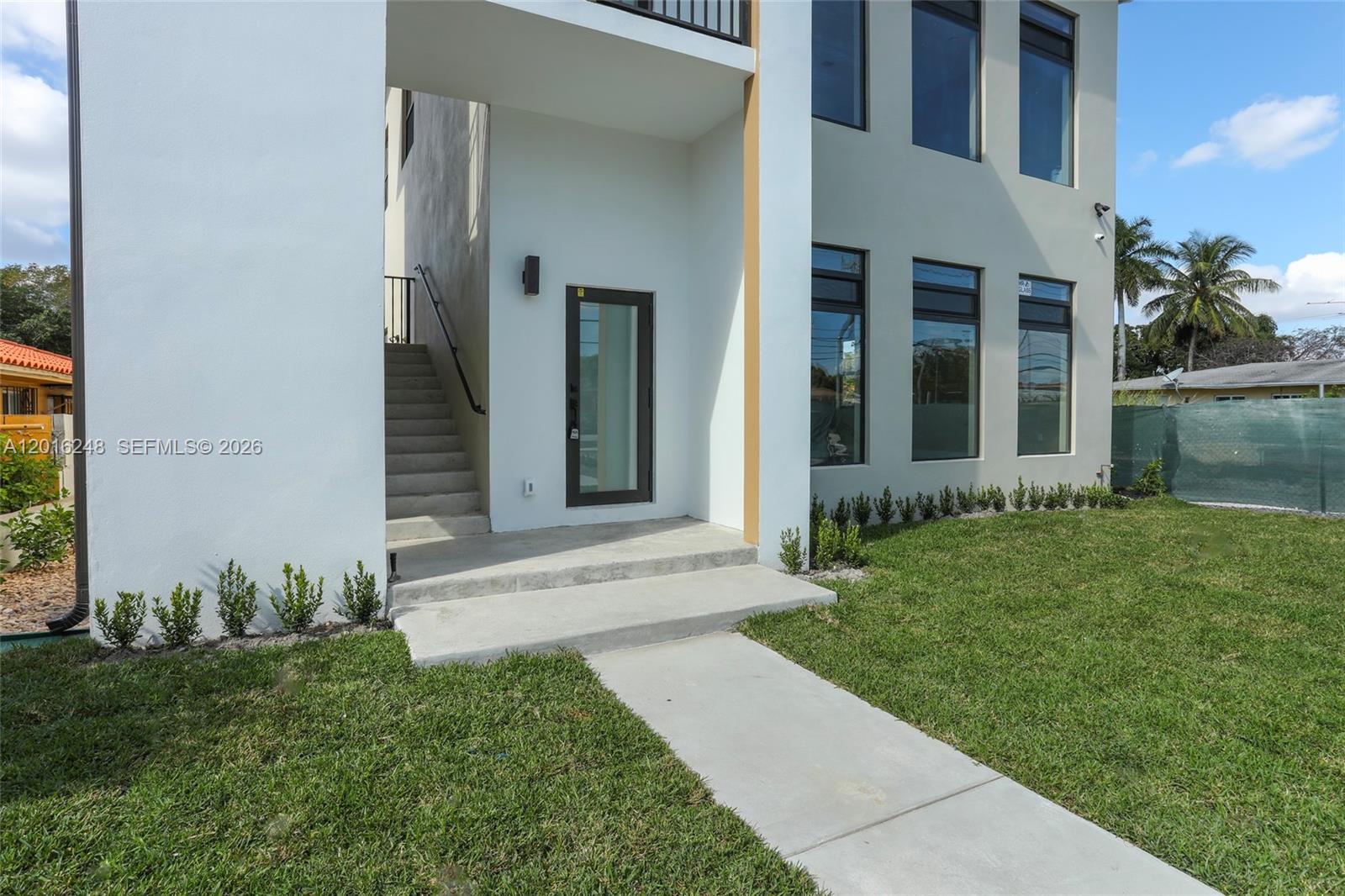 A modern white house exterior features a concrete walkway, stairs, and a glass-paneled door — 120 SW 35 Ave # A2, Miami FL 33135, MIAMI, FL