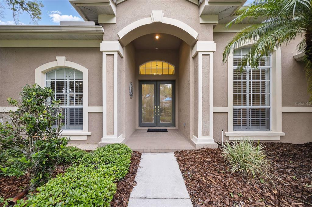 The exterior of a house features a covered entryway with double doors and two windows — 10232 ESTUARY DRIVE, TAMPA, FL
