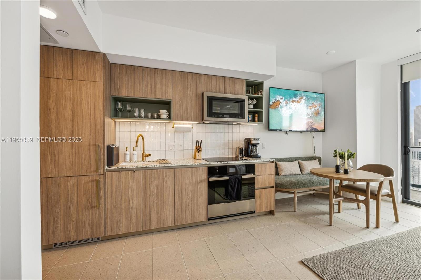 A modern kitchen features wood-grain cabinetry, stainless steel appliances, and an adjacent dining area — 159 NE 6th St # 3312, Miami FL 33132, MIAMI, FL