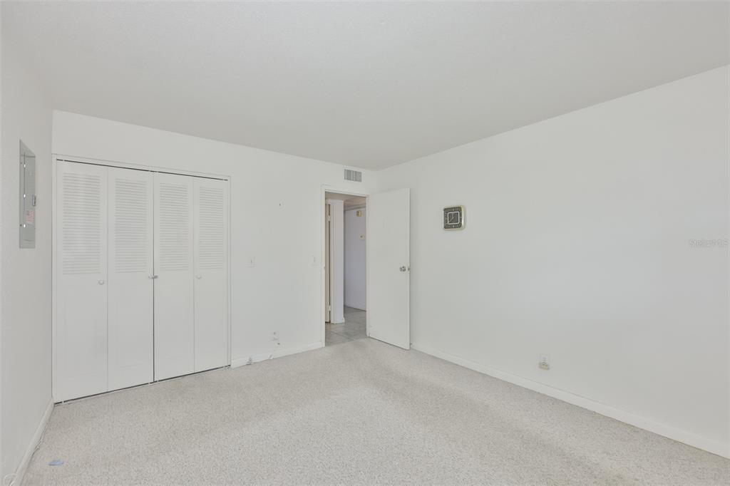 A bedroom with white walls, beige carpet, a white closet, and an open doorway — 1802 BEDFORD TERRACE UNIT 177, SUN CITY CENTER, FL