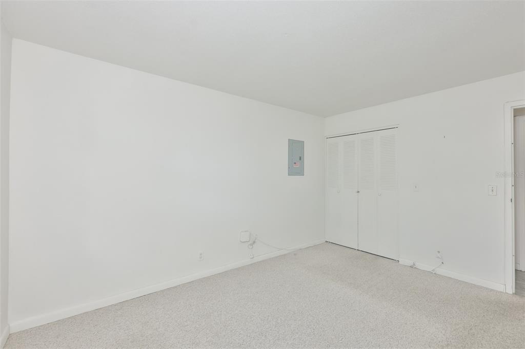 An empty bedroom with white walls, beige carpeting, a closet, and an electrical panel — 1802 BEDFORD TERRACE UNIT 177, SUN CITY CENTER, FL