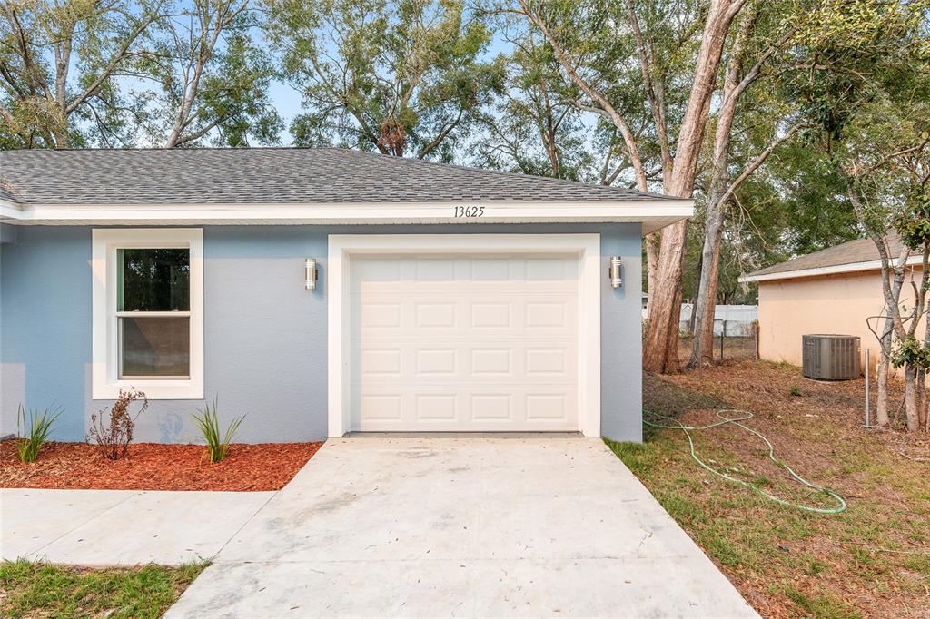 A light blue house exterior features a single-car garage and a concrete driveway — 3344 SW 151 COURT, OCALA, FL
