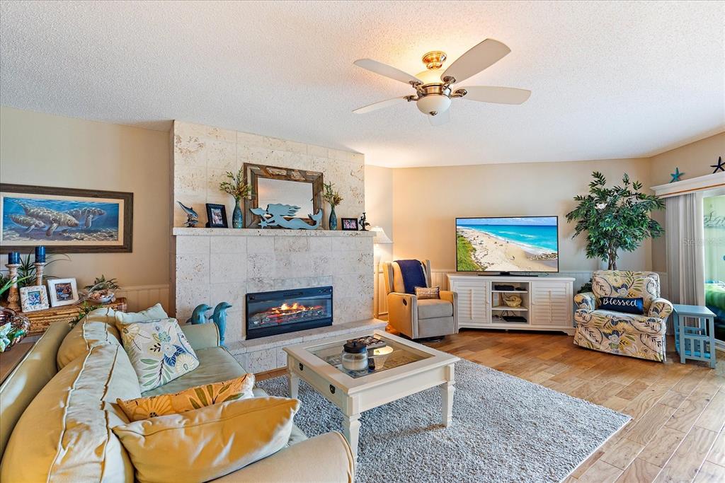A living room features a stone fireplace, a ceiling fan, and a television on a console — 5621 GULF OF MEXICO DRIVE UNIT 103, LONGBOAT KEY, FL