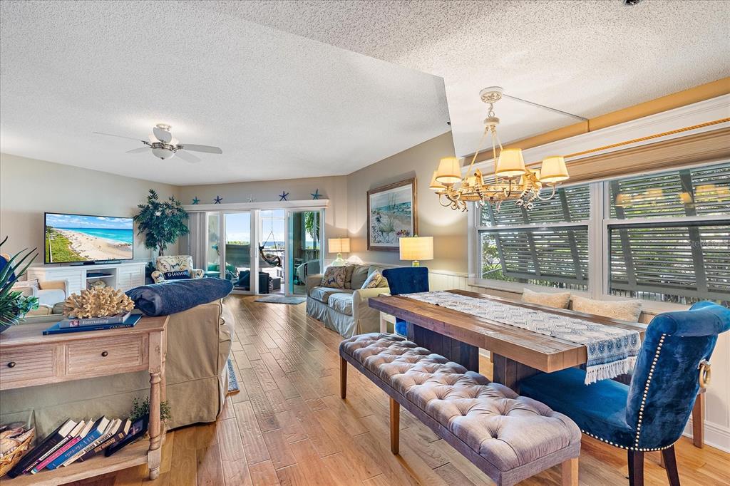 A living and dining area with wood floors, a chandelier, and a view of the ocean — 5621 GULF OF MEXICO DRIVE UNIT 103, LONGBOAT KEY, FL