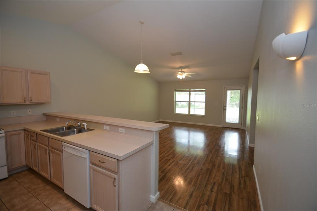 A kitchen with light wood cabinets and a breakfast bar overlooks an open living area — 37 ETON LANE UNIT B, PALM COAST, FL