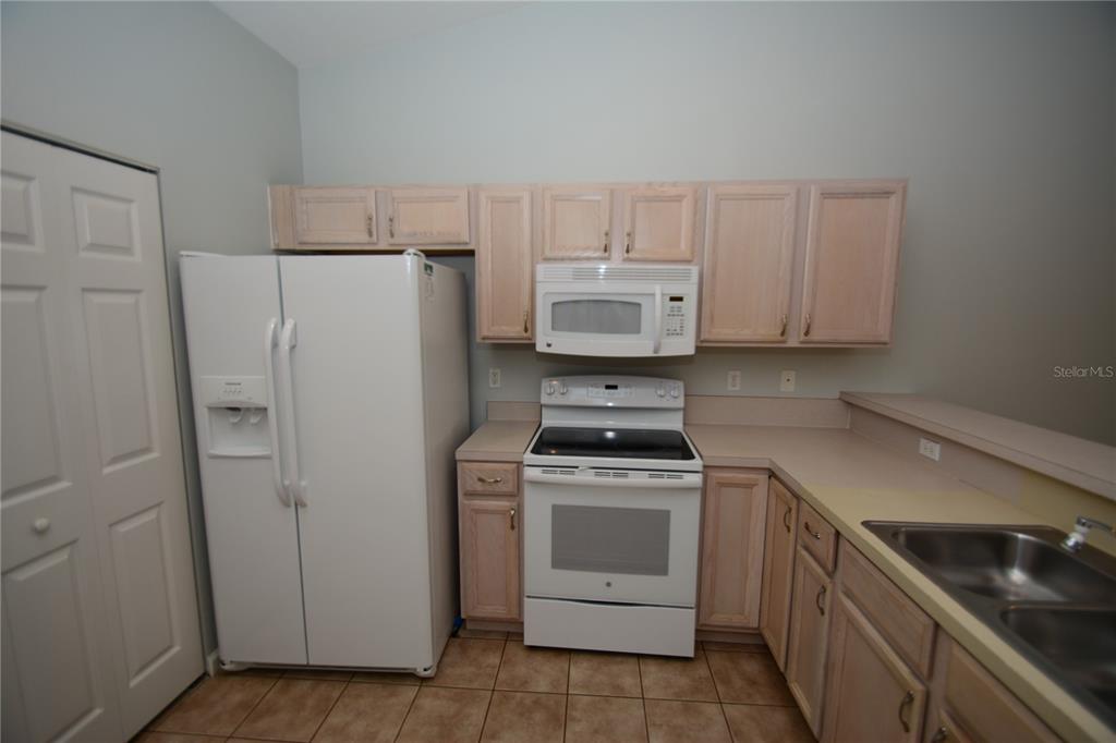 A kitchen features light wood cabinets, white appliances, a double sink, and tiled flooring — 37 ETON LANE UNIT B, PALM COAST, FL