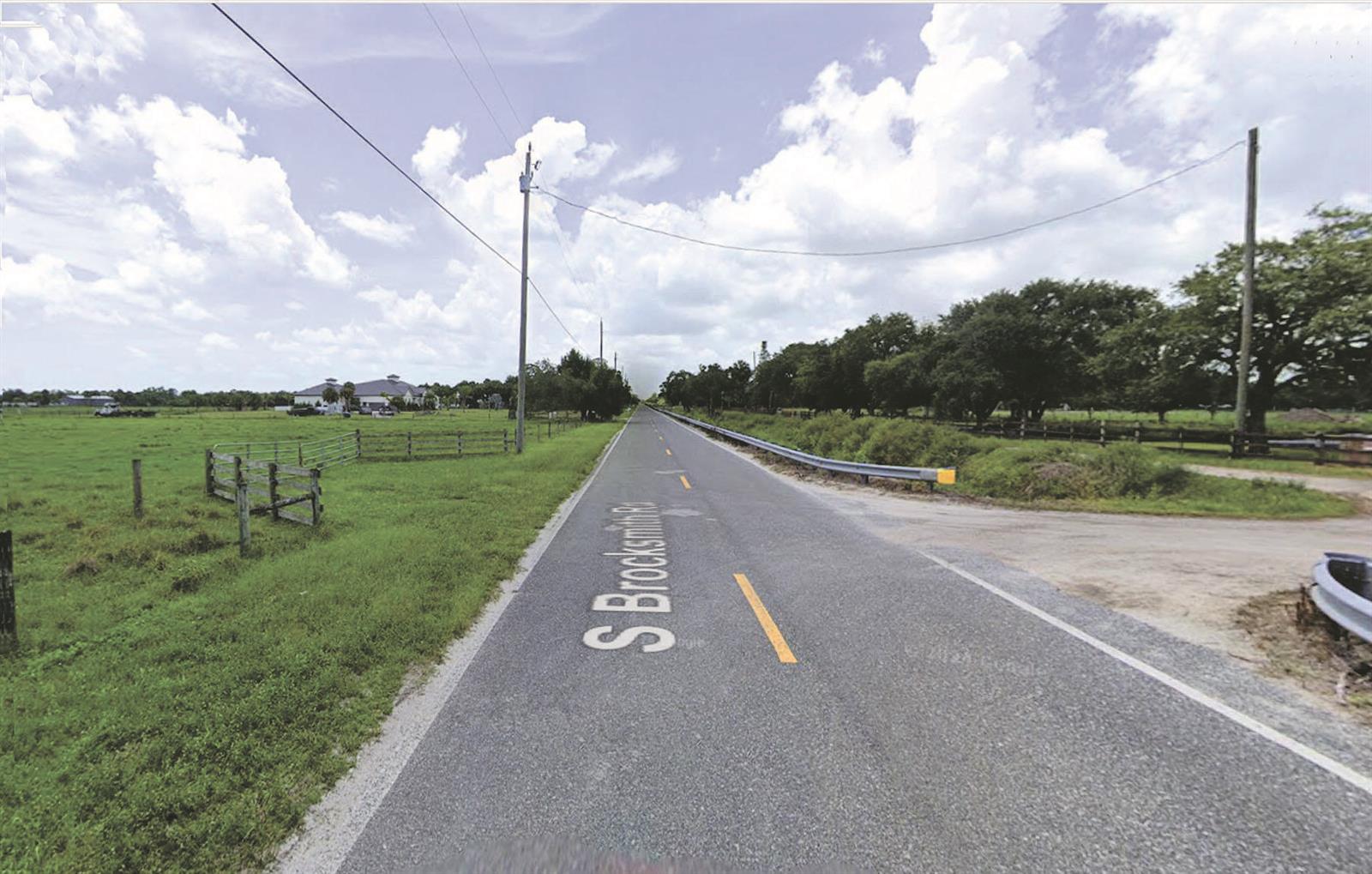 A paved road stretches into the distance past open green fields and utility poles — Tbd S Brocksmith Road, Fort Pierce FL 34945, FORT PIERCE, FL