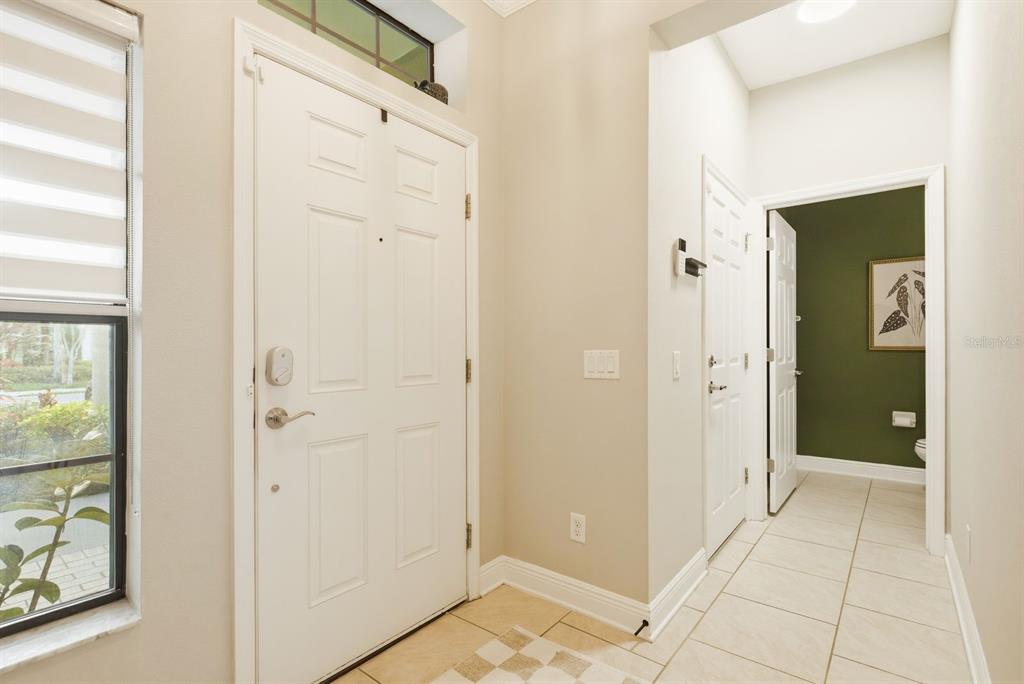 An entryway features a white front door, tiled flooring, and a doorway leading to a bathroom — 11636 CROWNED SPARROW LANE, TAMPA, FL